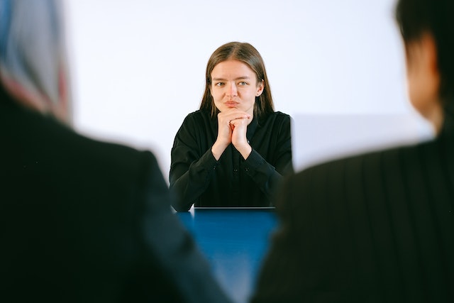 Woman in black blazer sitting being interviewed